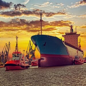 ship-with-tugboats-sunset